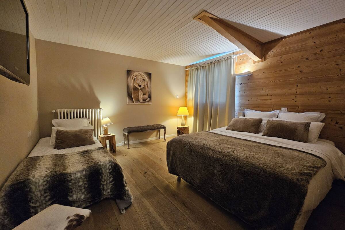 Une chambre d’hôtel avec deux lits, un banc, un tableau et des murs en bois.