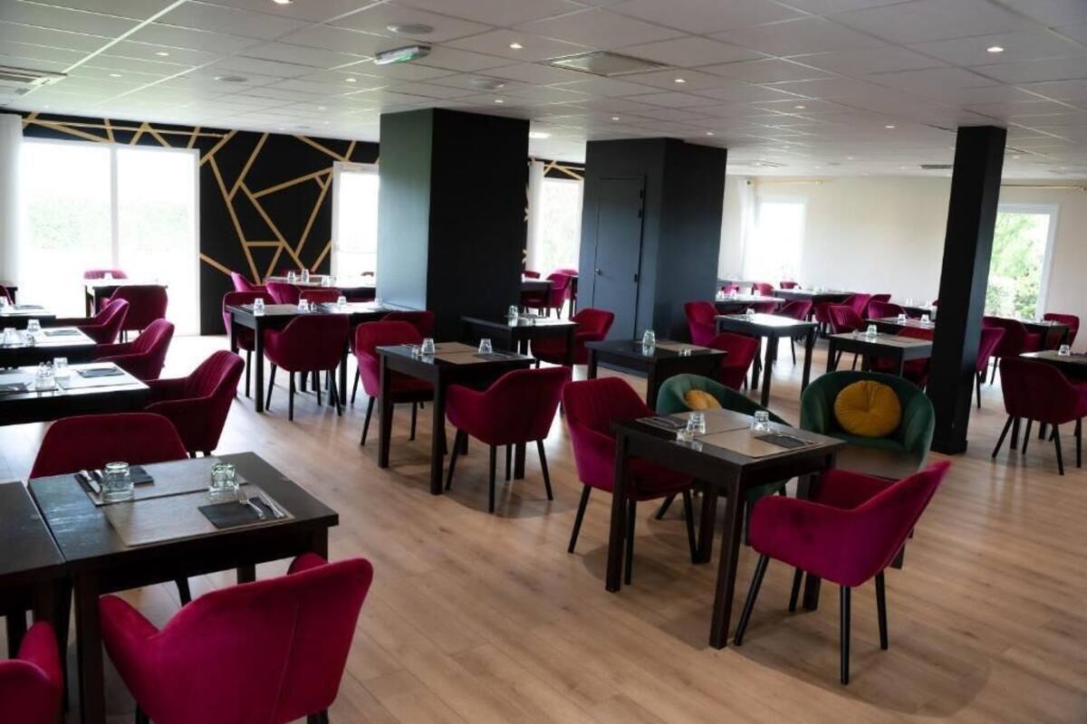 Un restaurante moderno con sillas rojas y verdes, mesas de madera y un diseño geométrico en la pared.