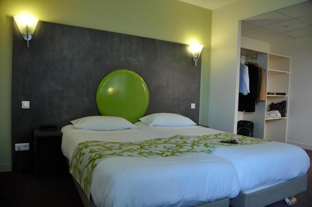 Ein Hotelzimmer mit einem großen Bett, zwei Nachttischlampen, einem Kleiderschrank und einem Schrank mit Kleidung.