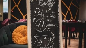 A chalkboard sign in a cafe with the words "Petit Déjeuner Breakfast" and various food and drink illustrations. - Brit Hotel Confort Alexia La Souterraine (La Souterraine)