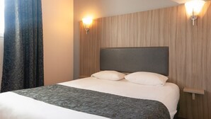A hotel room with a large bed, two bedside tables, and a headboard. - Brit Hotel Confort Alexia La Souterraine (La Souterraine)