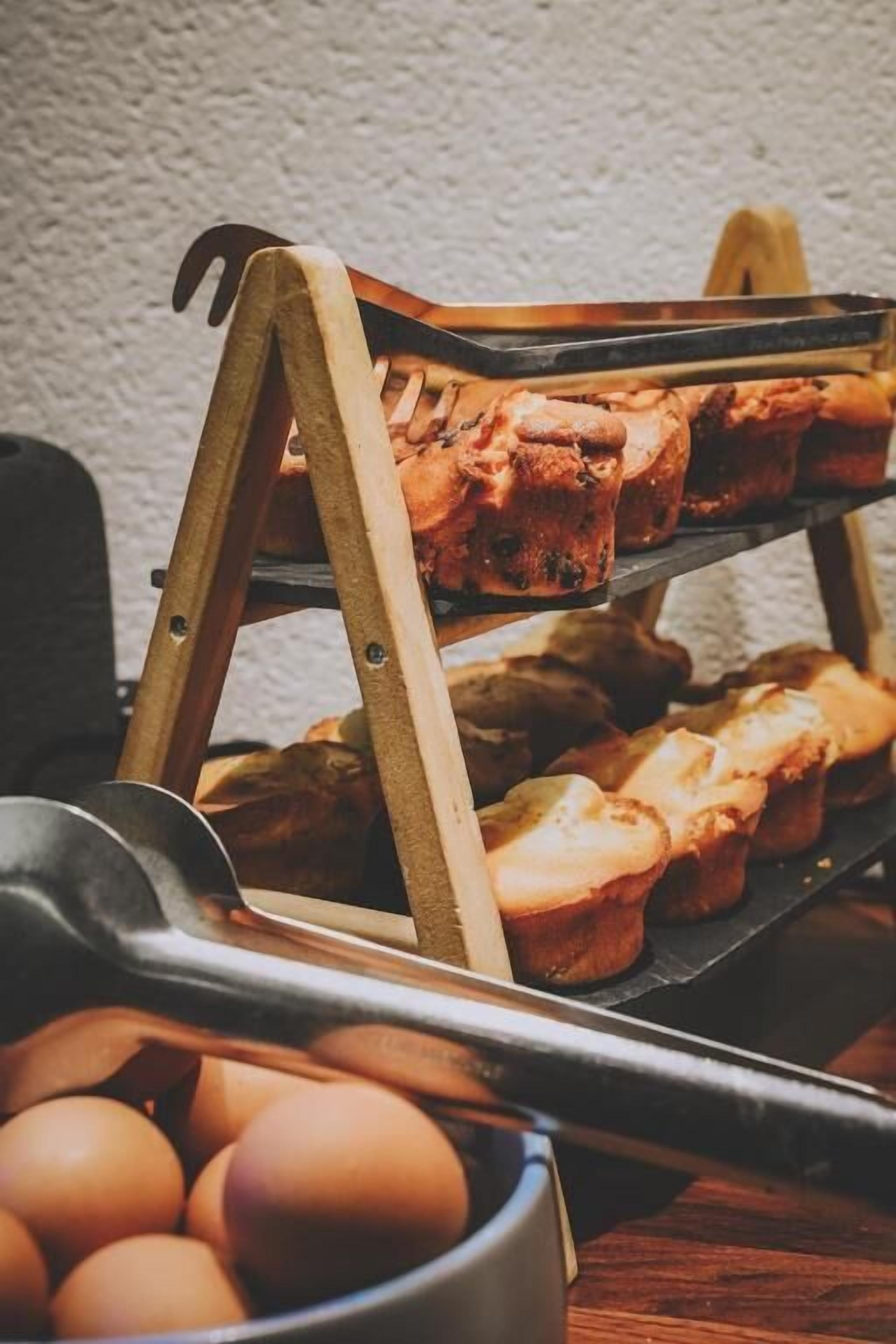 Un soporte de madera con muffins y un bol de huevos.