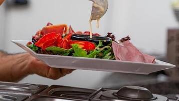 Una persona sosté un plat amb amanida i un ganivet.