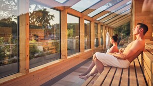 A wooden deck with large windows overlooking a garden. - Hotel Deimann (Schmallenberg)