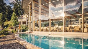 A modern building with a pool, outdoor seating, and a view of the surrounding landscape. - Hotel Deimann (Schmallenberg)