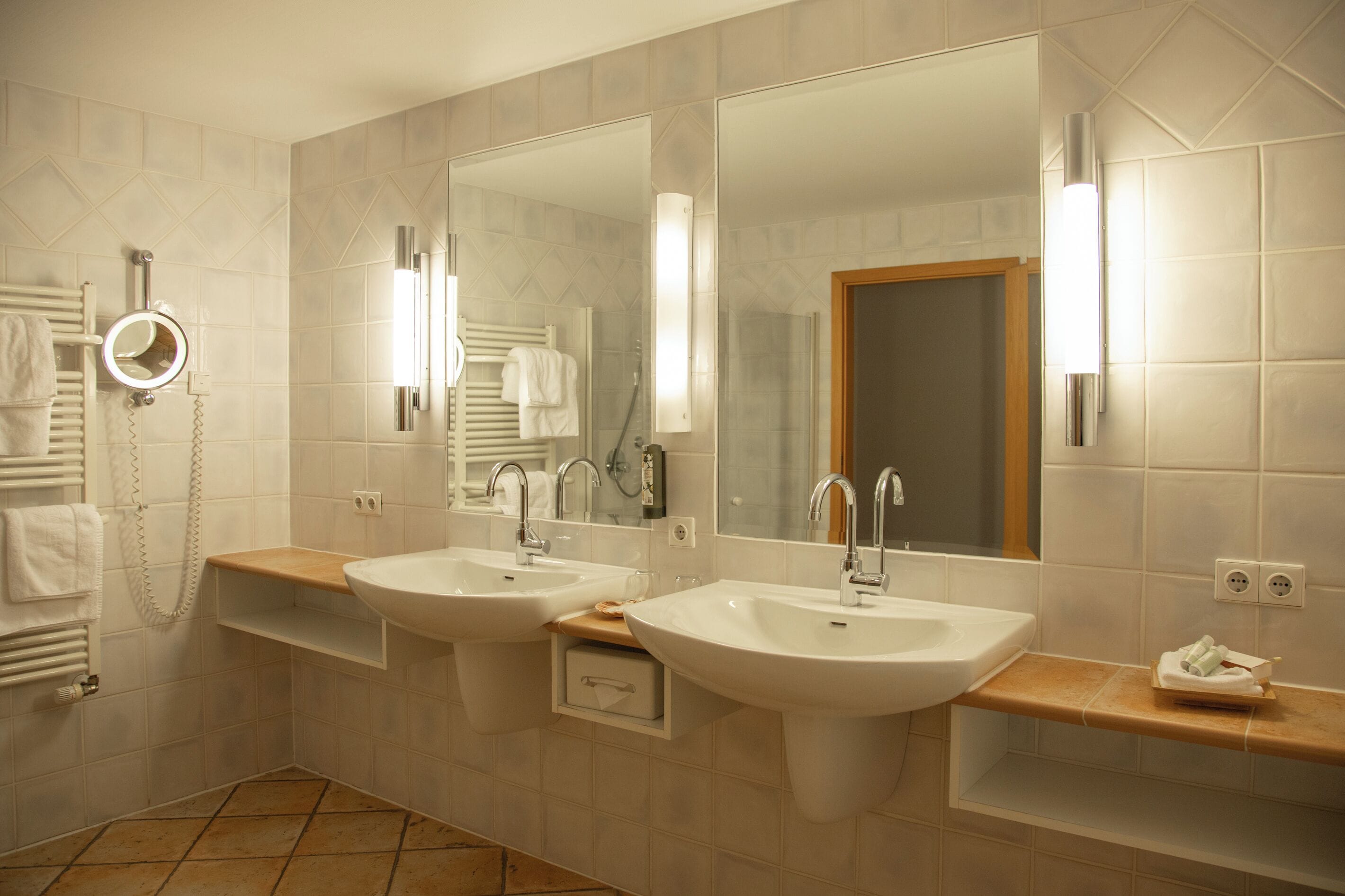 A bathroom with two sinks, a mirror, and a towel rack.