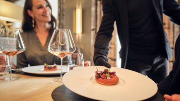A dining table with a dessert plate, wine glasses, and a person in a suit.