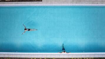 Vue aérienne d’une piscine rectangulaire dont les bords sont recouverts de carreaux et qui est bordée de pierres sur sa partie supérieure.