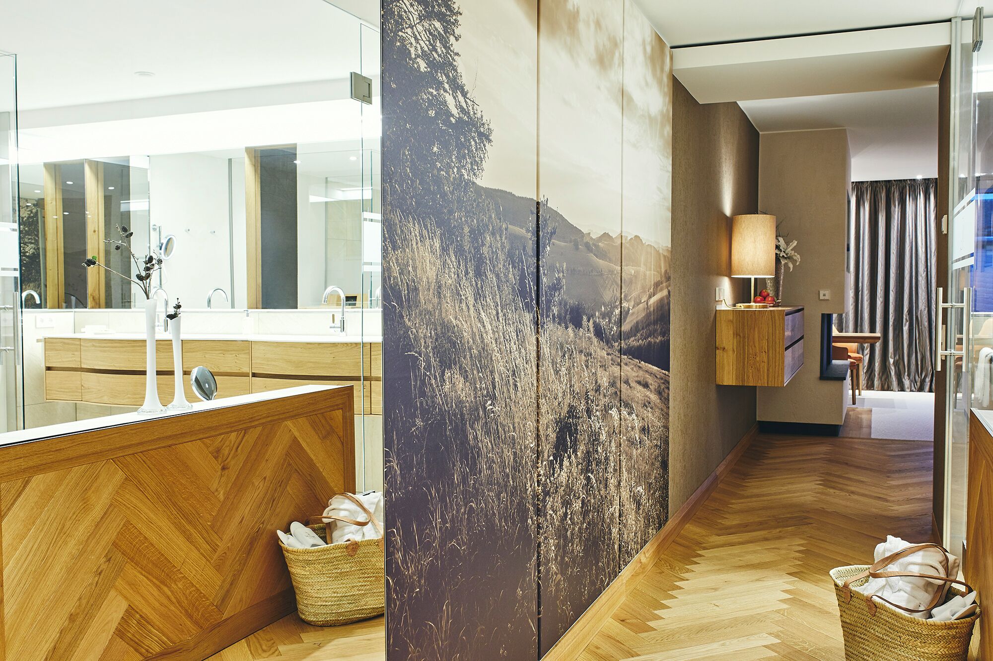 Un baño moderno con tocador de madera, un espejo grande y un mural con vistas panorámicas.