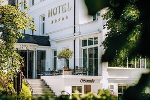 Un hotel con restaurante y bar de cervezas en la planta baja, terraza al aire libre y una escalera que conduce a la entrada.