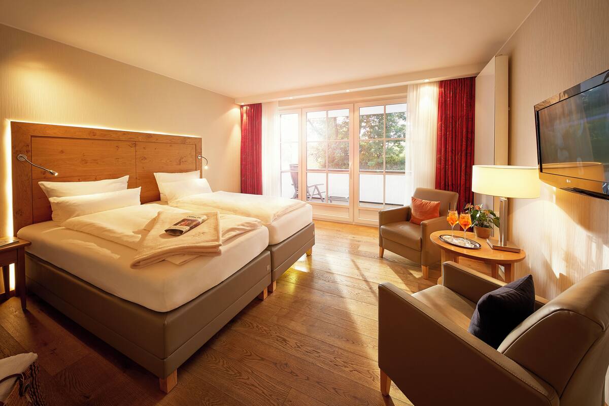 A hotel room with a double bed, a TV, a small table with a lamp, and a chair.