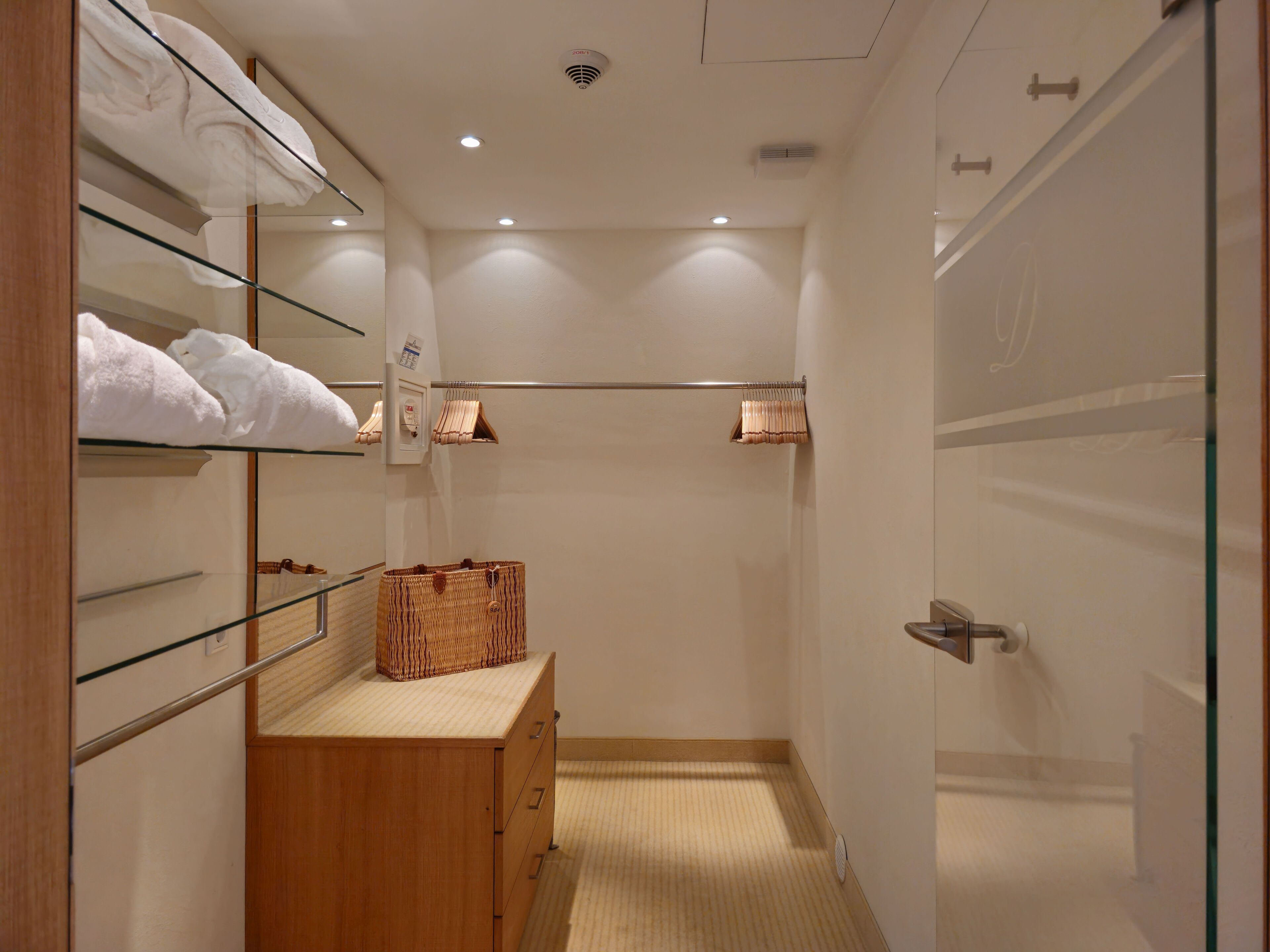 Une salle de bain d’hôtel avec un meuble-lavabo en bois, des porte-serviettes et une cabine de douche en verre.