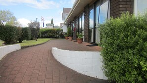 A motel with a brick facade, large windows, and a paved driveway leading to the entrance. - Ace Motor Lodge (Rotorua)
