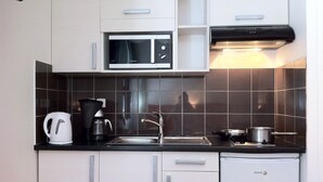Een kleine keuken met een magnetron, koffiezetapparaat, spoelbak en een vaatwasser.