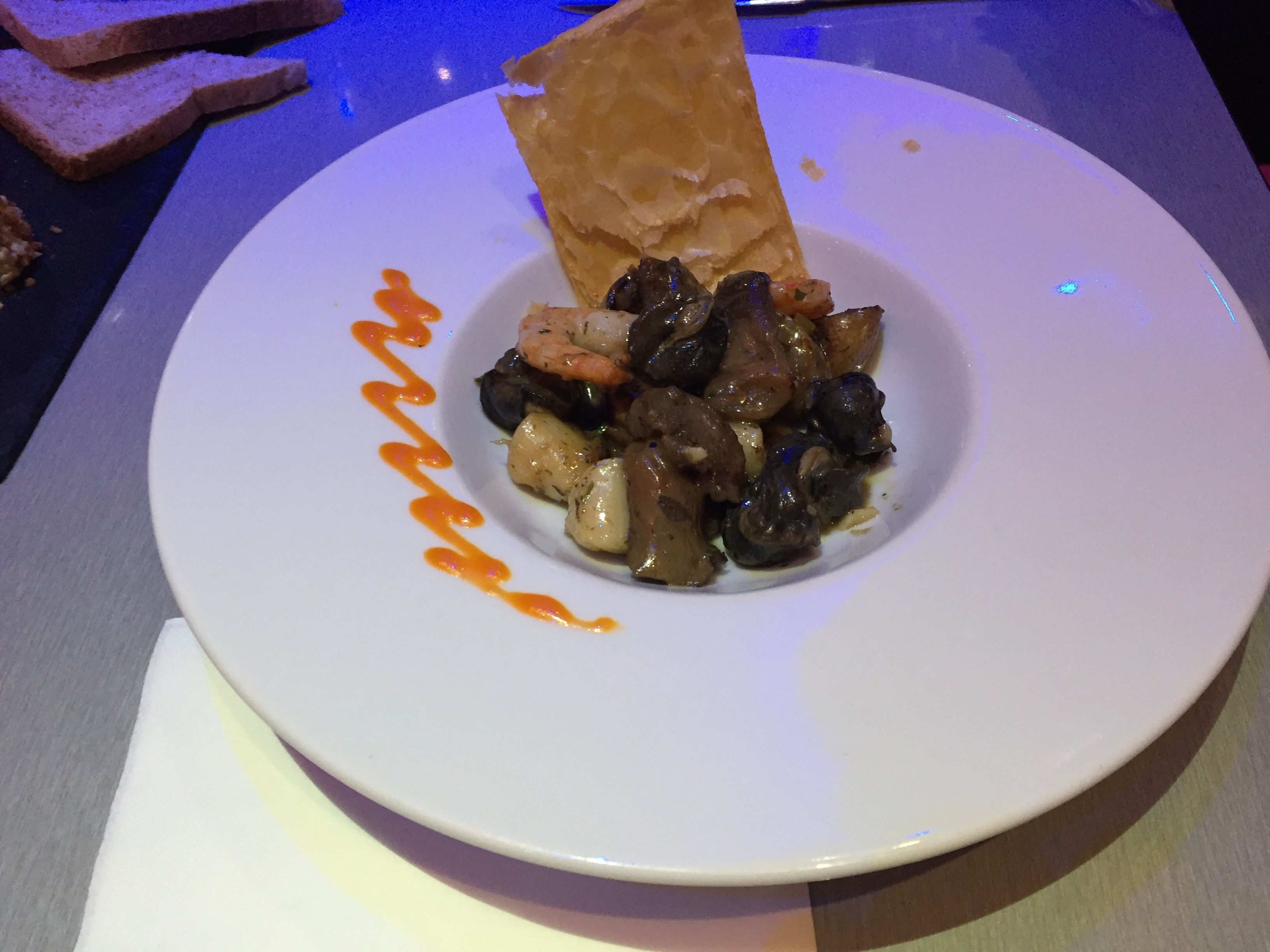 Ein Teller mit Brot und einer Portion Essen, möglicherweise ein Eintopf oder Auflauf, mit Soße darüber geträufelt.