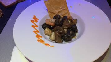 Ein Teller mit Brot und einer Portion Essen, möglicherweise ein Eintopf oder Auflauf, mit Soße darüber geträufelt.