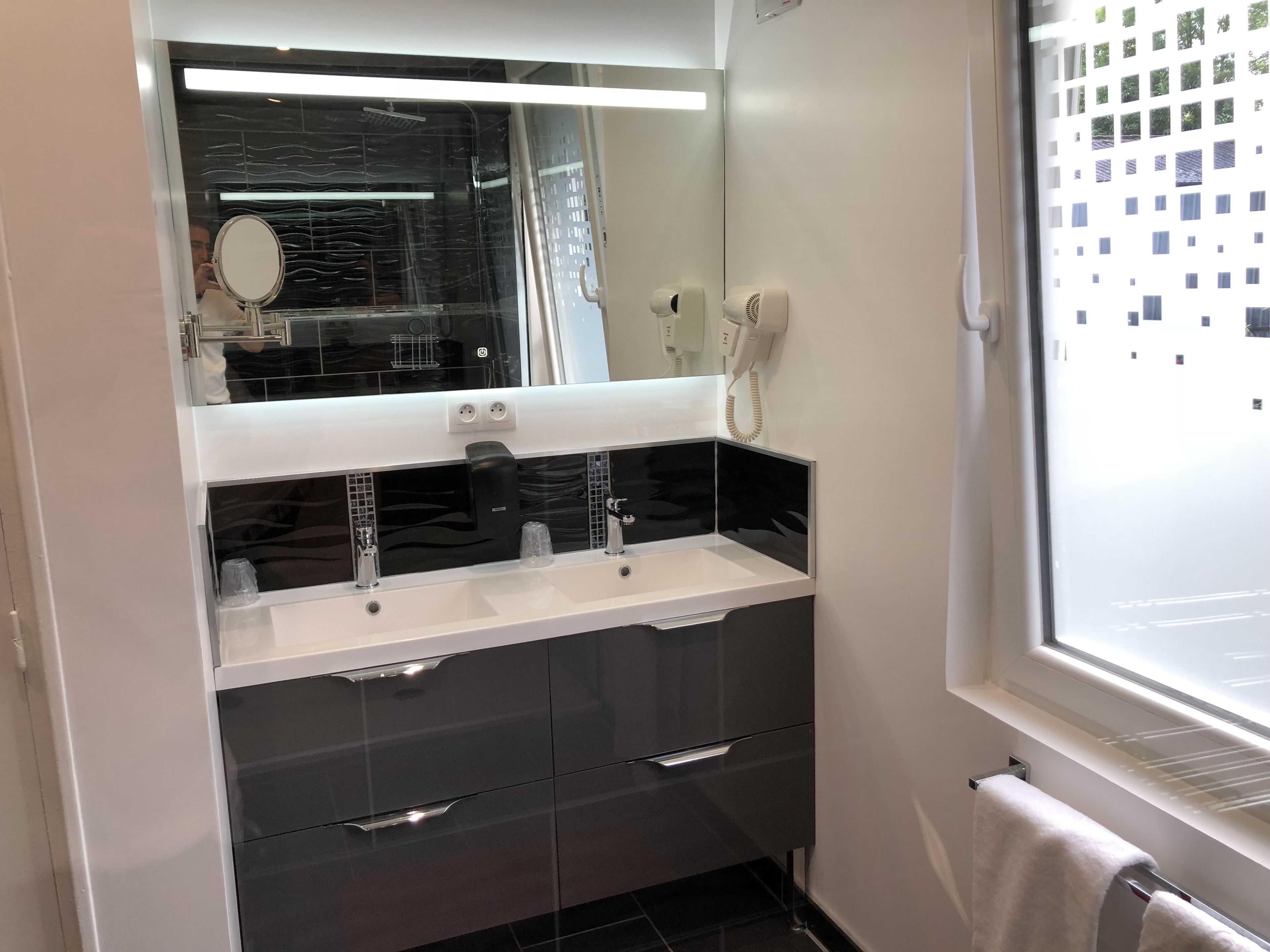 Un baño moderno con un espejo grande, un secador de pelo y un teléfono.