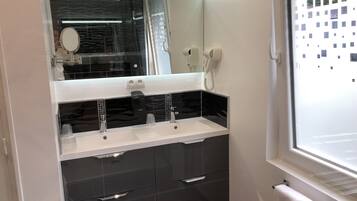 Un baño moderno con un espejo grande, un secador de pelo y un teléfono.
