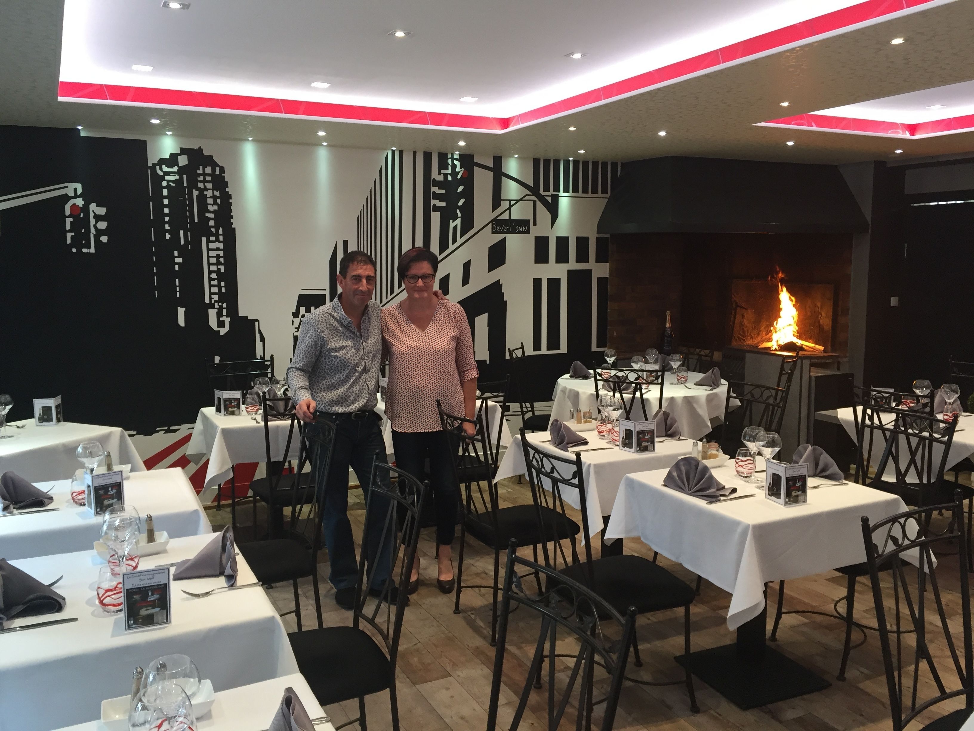 Een restaurant met gedekte tafels, een open haard en een modern interieur.