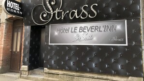 Señal de hotel que indica 'Strass' y 'Hôtel Le Beverl'Inn Sa Suite', mostrando que el hotel ofrece suites.