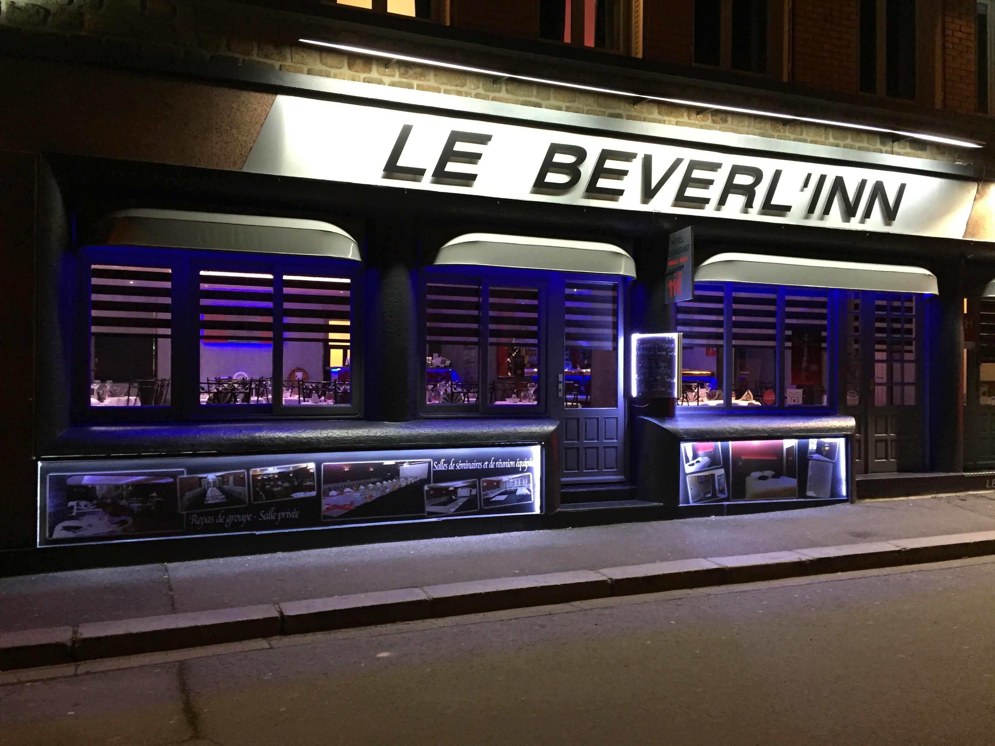 The exterior of Le Beverlinn hotel with illuminated signage and large windows.