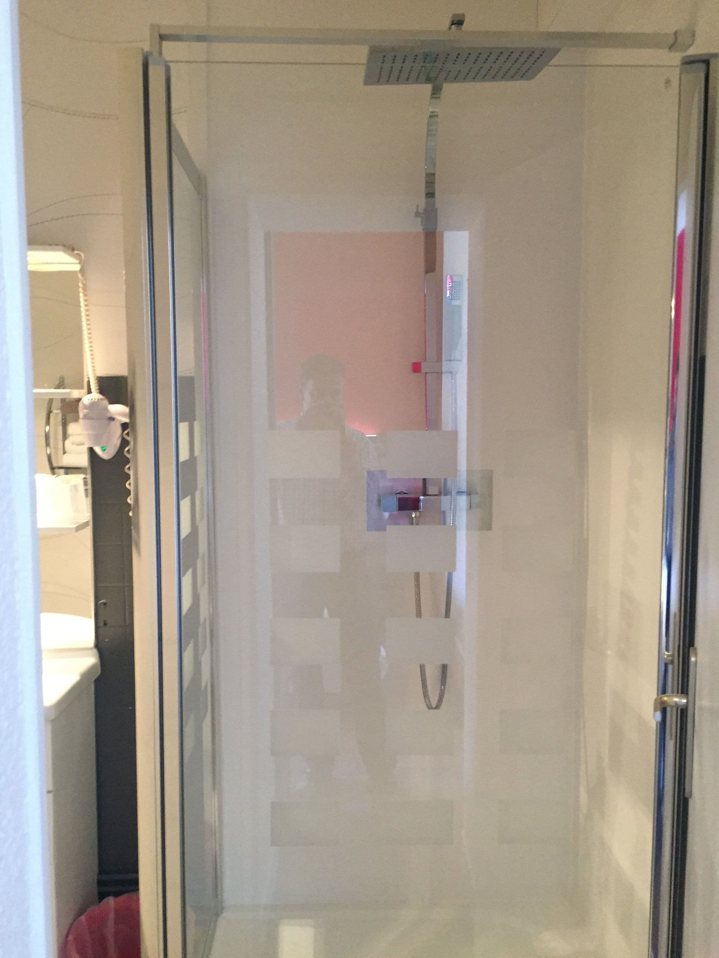 A glass-enclosed shower area with a visible hand dryer and a towel rack.
