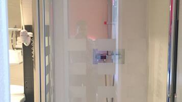 A glass-enclosed shower area with a visible hand dryer and a towel rack.
