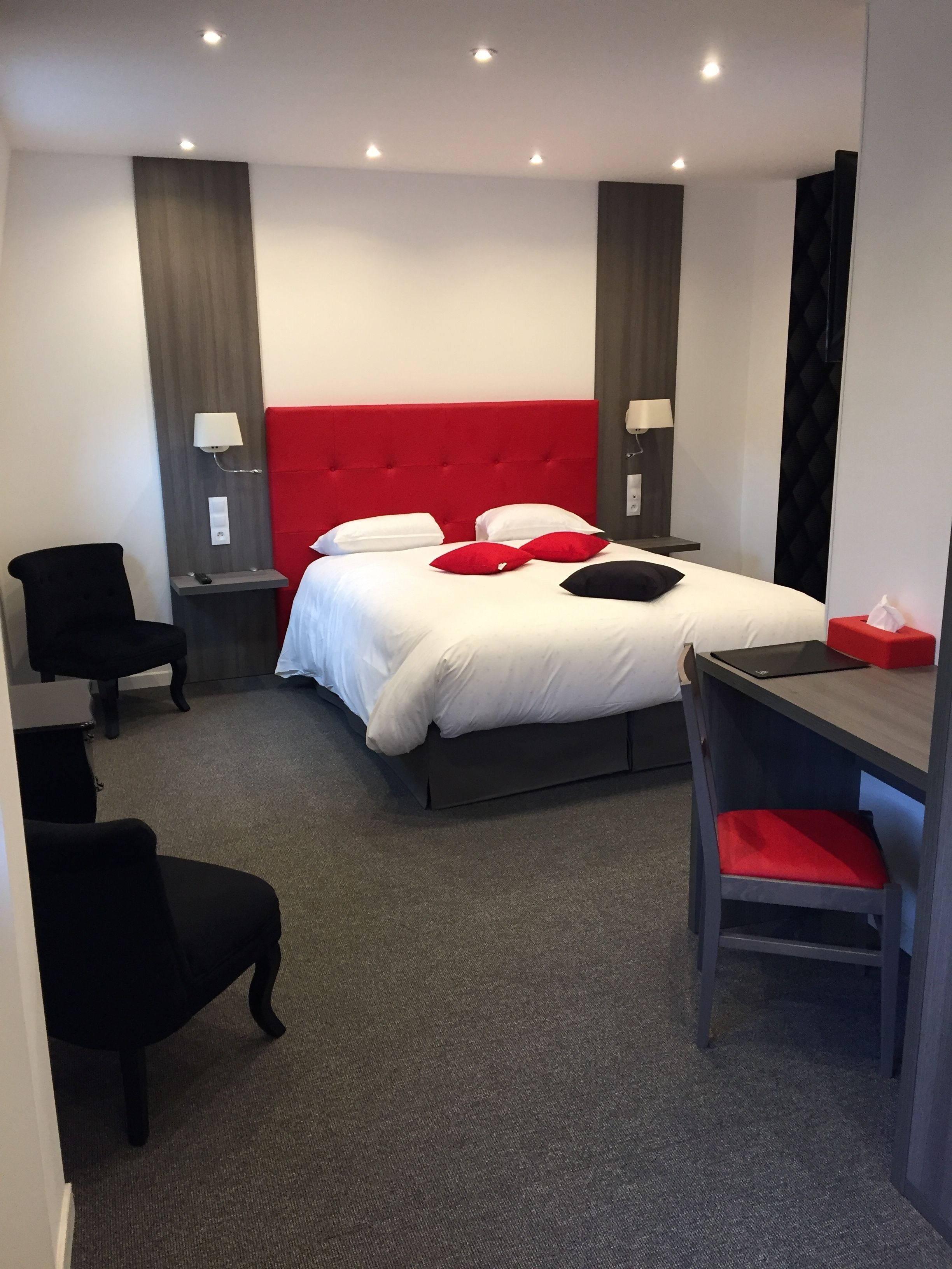 Una habitación de hotel con cama, escritorio, silla y mesita de noche.
