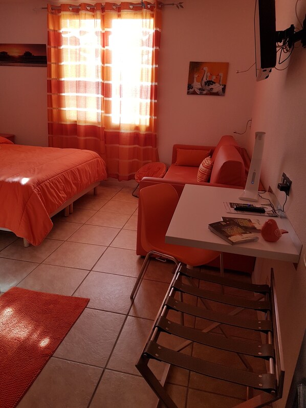 A room with a bed, a desk, and a chair. There is a window with curtains, a painting on the wall, and a lamp on the desk. - Logis Hotel Corintel, Bordeaux Est (Tresses)