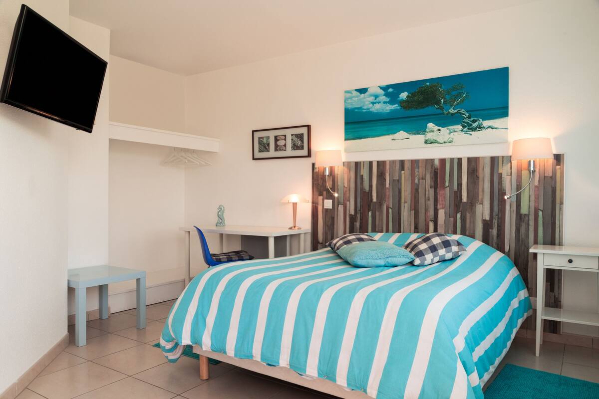 A bedroom with a bed, a desk, and a chair.