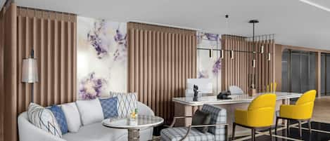 A modern hotel room with a sofa, armchair, dining table, and chairs.