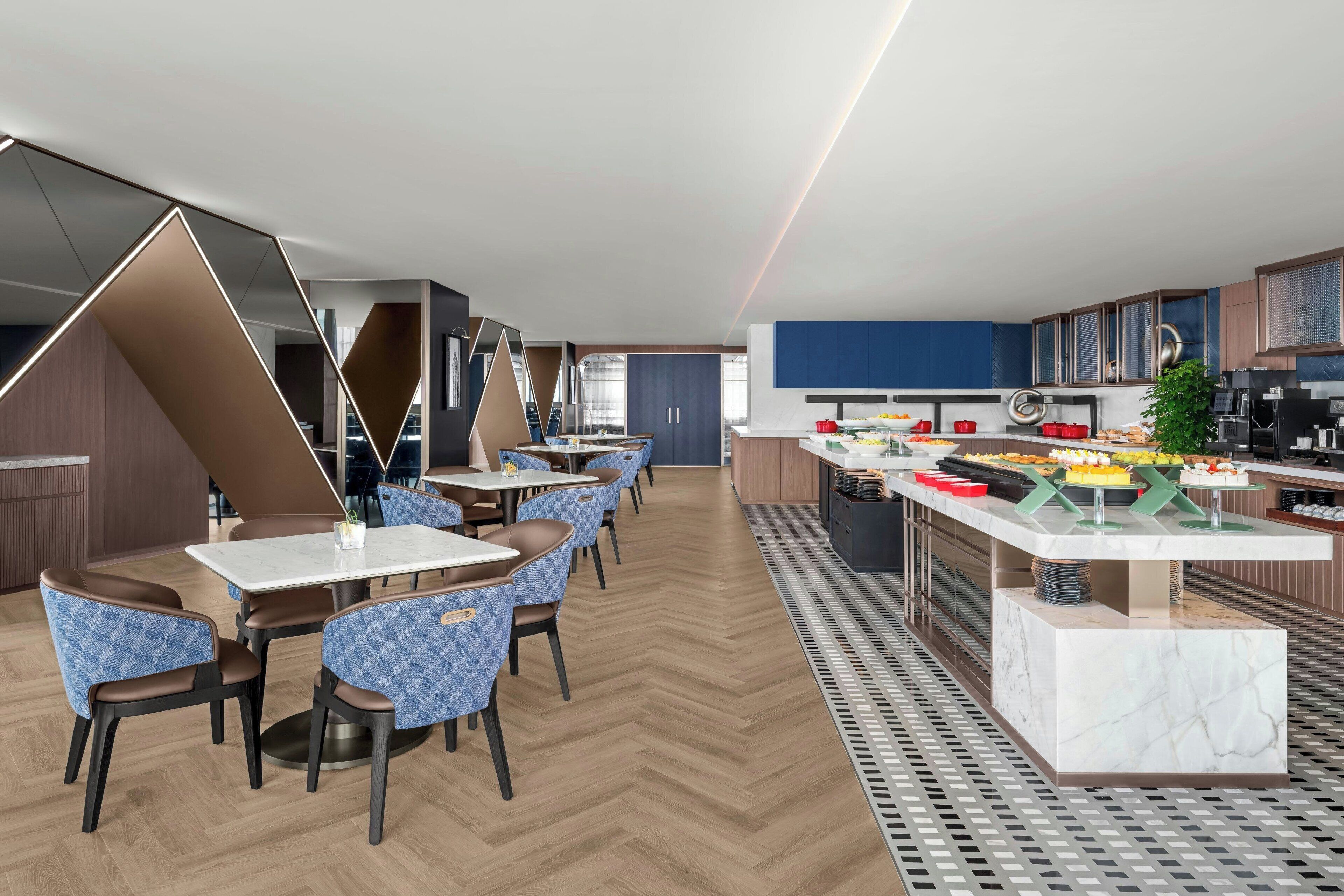 Zona pranzo moderna con buffet, sedie blu a motivi decorativi e pavimento in legno a spina di pesce.