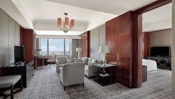 A hotel room with a large window, a chandelier, a sofa, a desk, and a television.