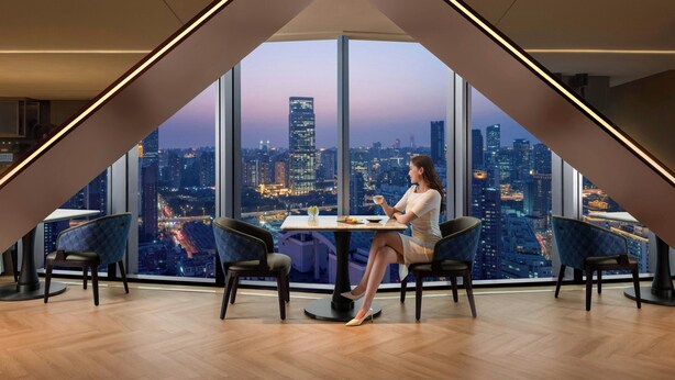 Un comedor moderno con vistas panorámicas a la ciudad, que incluye una mesa, sillas y un ventanal grande.
