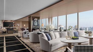 Un moderno vestíbulo de hotel con un amplio espacio de estar, un bar y un ventanal con vistas a la ciudad.