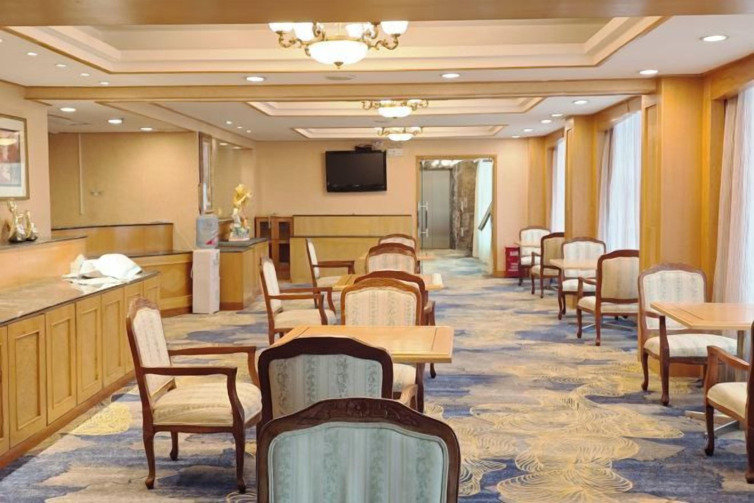 Un comedor de hotel con una barra larga, varias mesas y sillas.