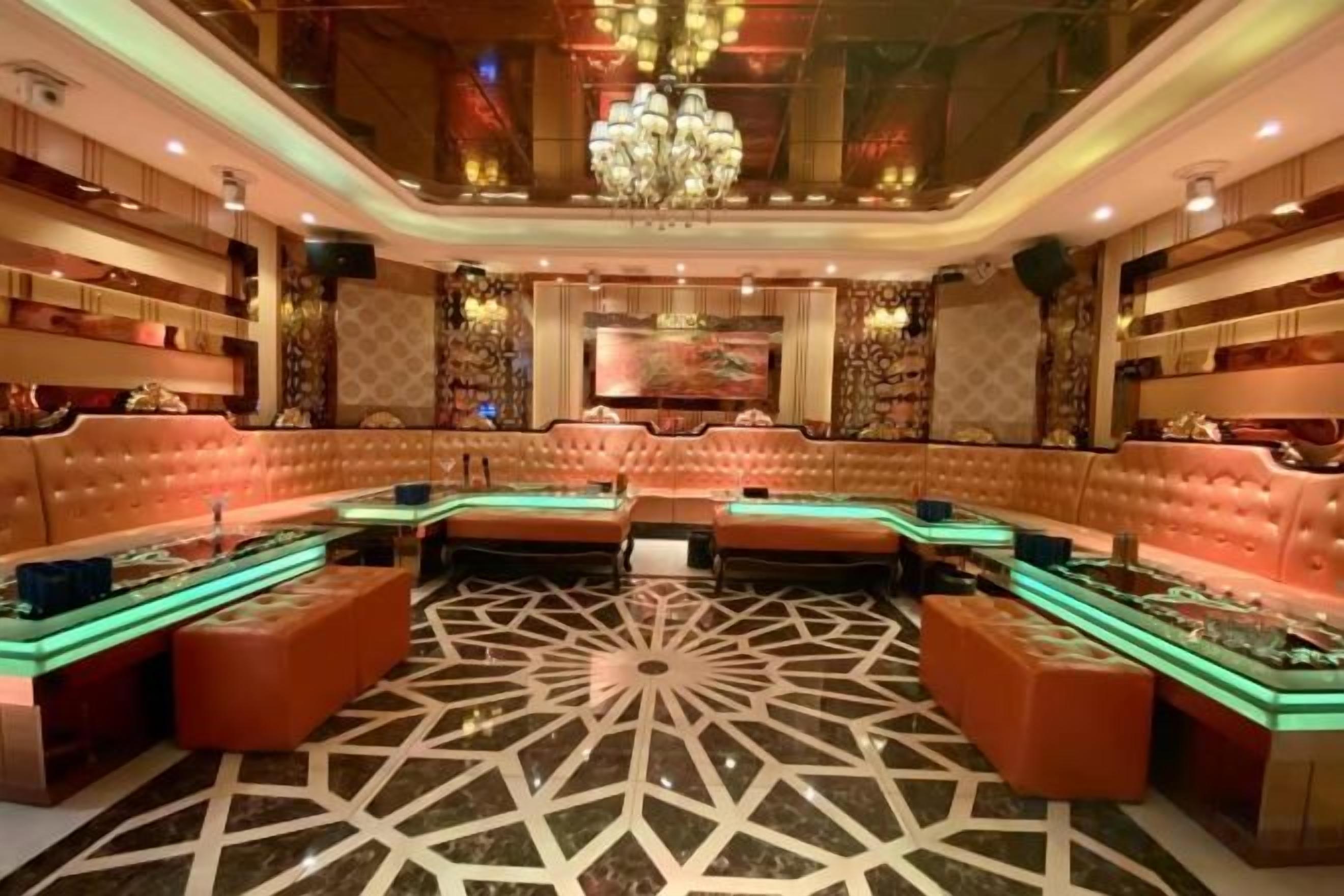 A luxurious lounge area with plush seating, a patterned floor, and ambient lighting.
