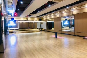 A spacious dance studio with a wooden floor, mirrors, and a large window.