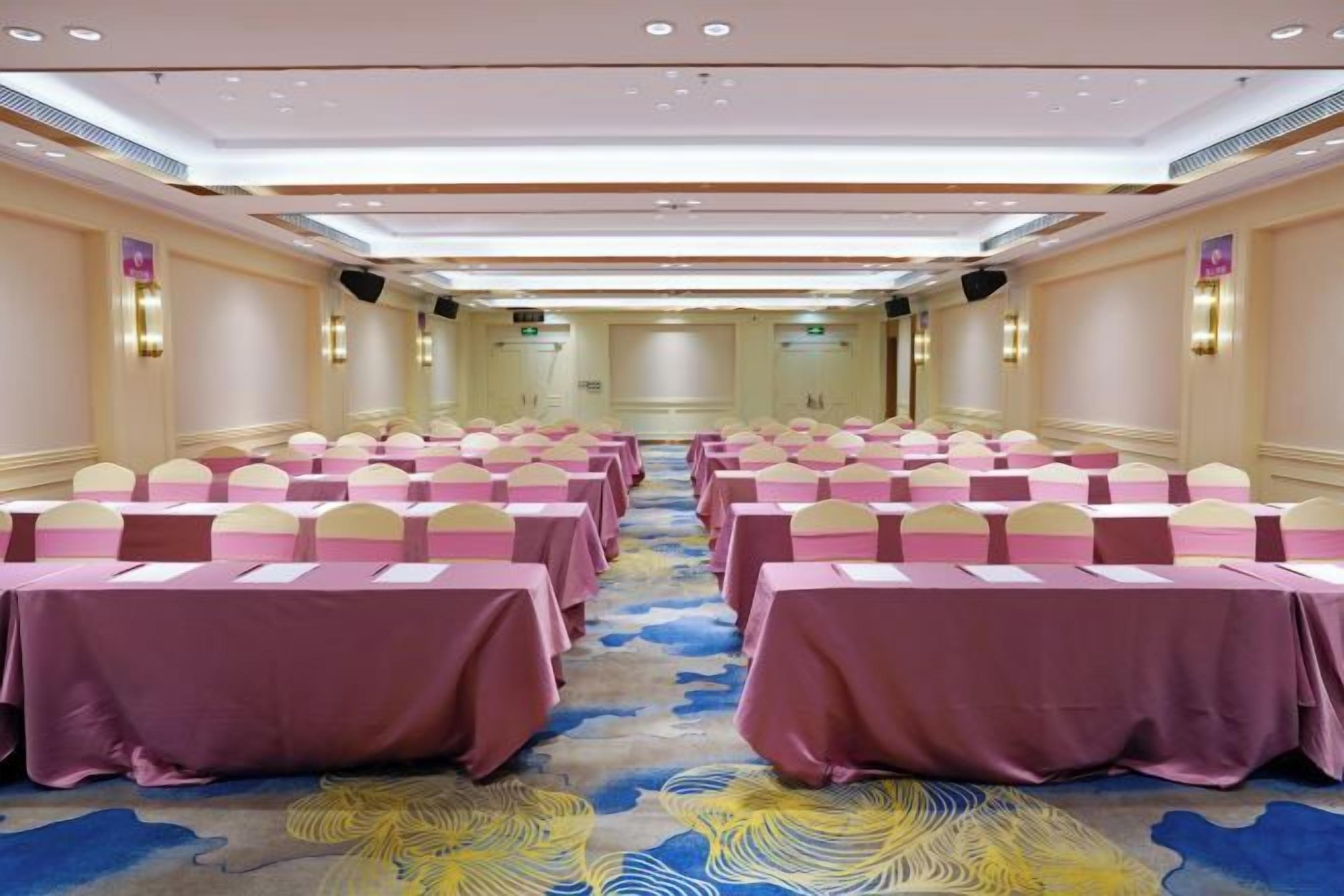 A conference room with rows of tables and chairs, a patterned carpet, and a neutral color scheme.