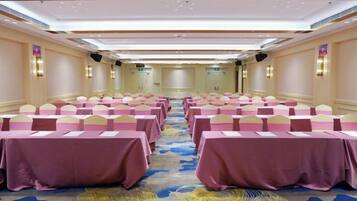 A conference room with rows of tables and chairs, a patterned carpet, and a neutral color scheme.