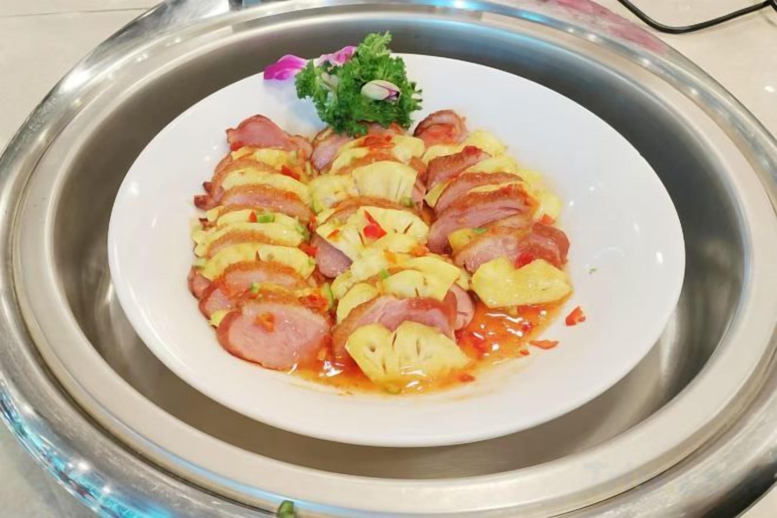 Un plato de comida con carne en rodajas y piña sobre un plato blanco.