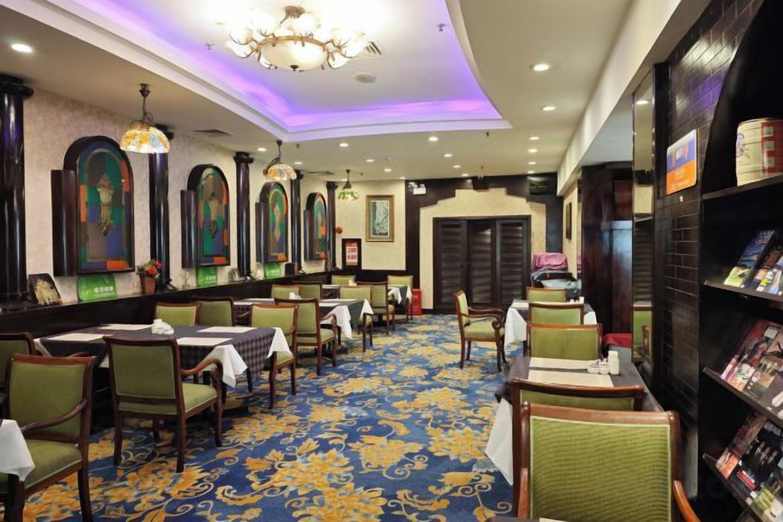 A restaurant with tables and chairs, a patterned carpet, and a chandelier.