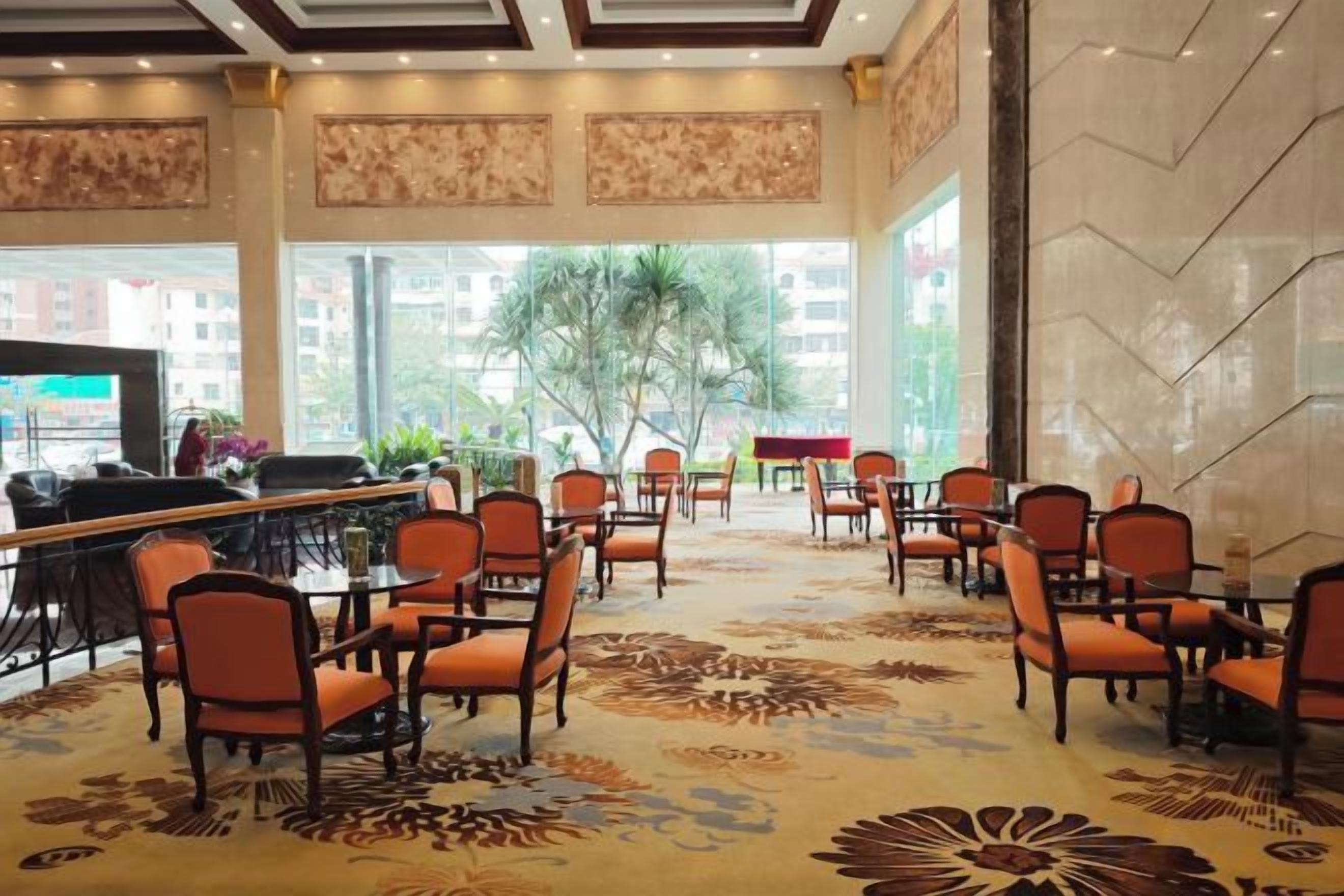 Un hall de hotel con mostrador de recepción, zona de estar y grandes ventanales.