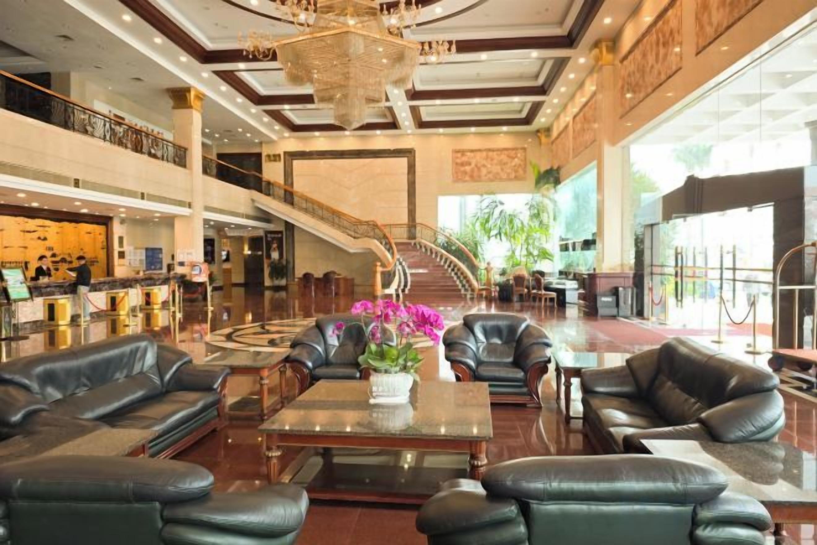 A spacious lobby with leather seating, a central coffee table, and a staircase leading to upper floors.