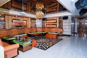 A spacious lobby with leather seating, a patterned rug, and a large chandelier. - Gladden Hotel (Fenggang Town) (Dongguan)