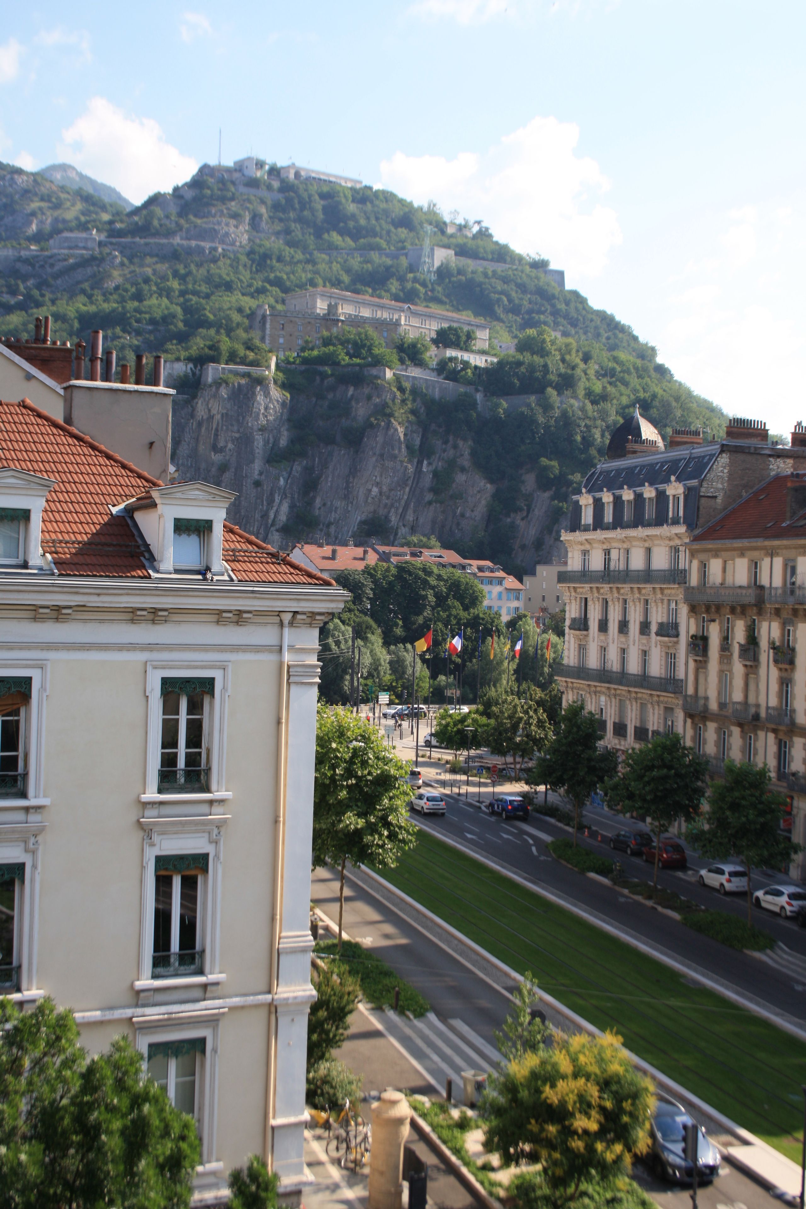 A cityscape with buildings, a road, and a hill with a fortification.