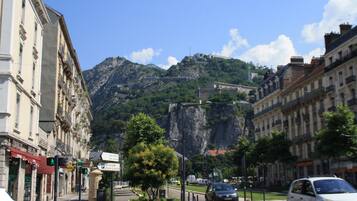 A street with buildings, a mountain, and a car.