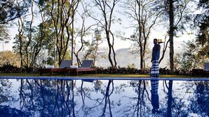 A pool with reflections of trees and a person carrying a tray.