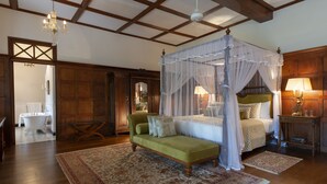 A bedroom with a four-poster canopy bed, a green sofa, and a wooden floor.