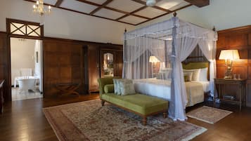 Ein Schlafzimmer mit einem Himmelsbett, einem grünen Sofa und Holzboden.
